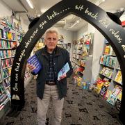 Derek Sturch, new Devon-based author standing in Archway Bookshop in Axminster holding his two books.